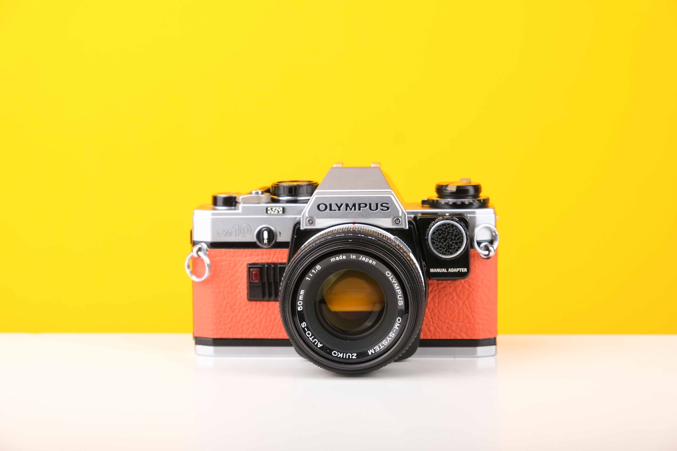 Olympus OM10 35mm SLR Film Camera with Manual Adapter and Olympus Zuiko Auto-S 50mm f1.8 Lens in Orange